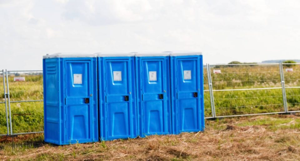 Defocus four blue of portable bio toilet cabins in field. Line of chemical toilets for the holiday, festival and crowd. WC. Workers using the portable restroom on a construction site. Out of focus.